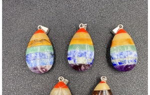 Detailed close-up of teardrop-shaped seven chakra stones layered in a rainbow pendant