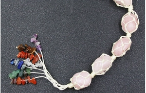 Macro detail of hand-woven pink quartz raw stones and colorful chakra crystal fringe