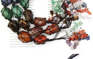 Close-up of handmade woven crystal pendant featuring colorful raw gemstones and tiger eye