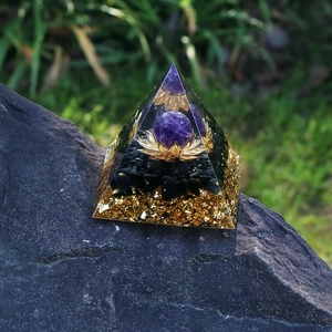 Detailed macro view of an Orgone pyramid with amethyst ball, lotus charm, and black obsidian