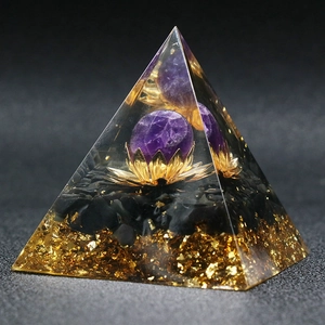 Macro view of Orgonite Pyramid with amethyst sphere and golden lotus in clear resin