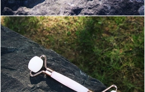 Dettaglio di un rullo facciale al quarzo rosa con impugnatura in oro rosa su pietra scura