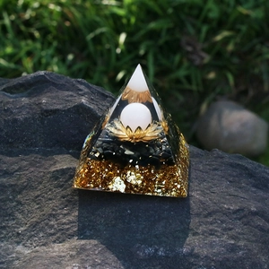 6cm Orgone crystal pyramid with lotus and white orb on a natural rock background