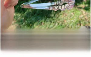 Macro view of silver cuff bracelet set with round pink crystals on a green background