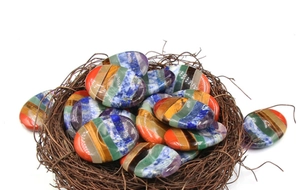 Dettaglio macro di sette pietre chakra naturali disposte in un nido decorativo
