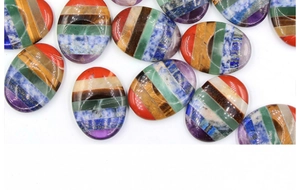 Vista macro di pietre pollice sette chakra ovali con strati colorati per guarigione e massaggio