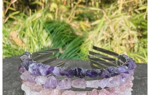 Close-up of handmade raw crystal crowns with amethyst and rose quartz on a stone surface