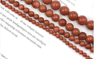 Detailed view of various sizes of brown gold sandstone beads arranged on vintage book