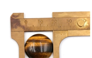 Misurazione di un cabochon occhio di tigre da 18mm con un calibro a corsoio in ottone