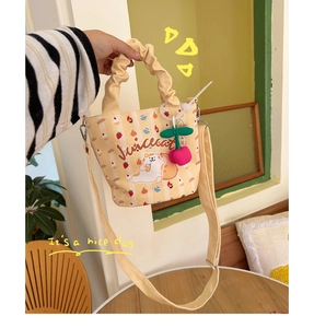 Detail of yellow canvas bucket bag featuring a cute cartoon cat and cherry plush charm