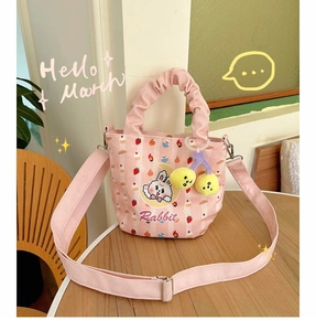 Detail of pink striped canvas bucket bag with rabbit print and pleated handle on wooden table