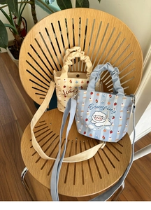 Detail of striped canvas bucket bags with cartoon prints and ruffled handles on a chair