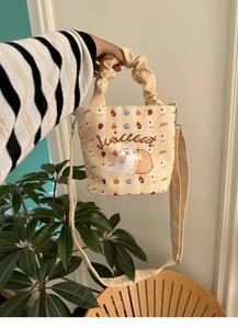 Detail of cute cat print on cream canvas bucket bag with ruffled handle and shoulder strap