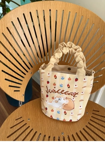 Close-up of beige canvas bag featuring cute cat print and ruched scrunchie handle