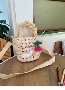 Detail of yellow striped canvas bucket bag with cat print and cherry charm