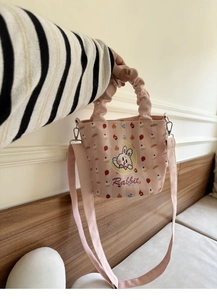 Detailed close-up of pink striped canvas bucket bag with rabbit print and pleated handle