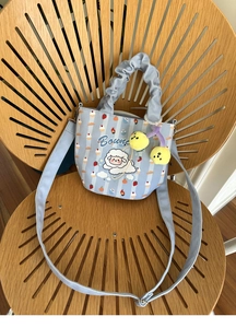 Detail of light blue canvas bucket bag with cute cartoon sheep patterns and plush charm