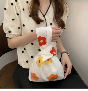 Close-up of Japanese knot bag with floral print worn by a model in a minimal setting