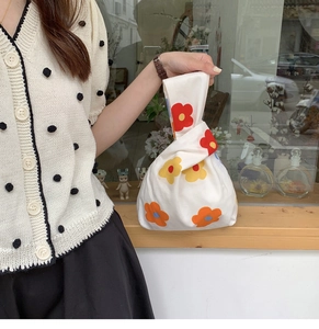 Close-up of a Japanese knot bag featuring orange and red floral prints on white cotton