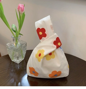 Close-up of a floral knot bag with colorful prints on a wooden table with tulips