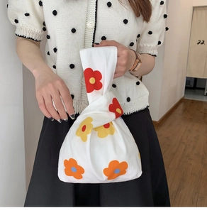 Detail of floral knit knot bag with vibrant red and yellow flowers for casual wear