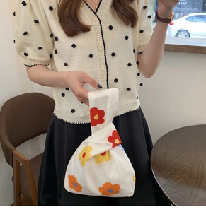 Detail showing white fabric wrist bag with vibrant yellow and orange floral patterns