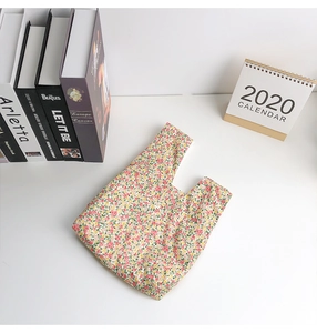 Close-up of floral canvas wrist bag with red and yellow pattern on white desk