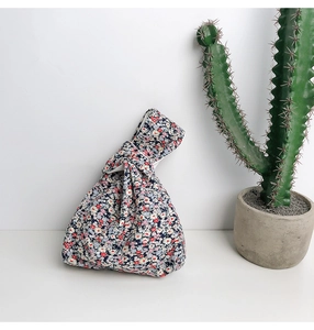 Close-up of Japanese floral pattern wrist knot bag in navy blue cotton linen fabric