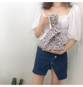 Floral knot wrist bag held by model, featuring Japanese style patterns on canvas fabric