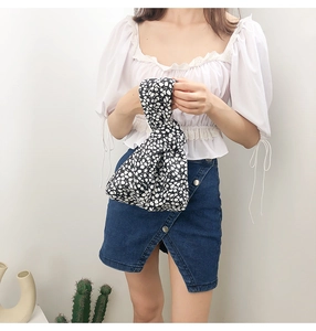 Japanese floral knot wrist bag shown with casual outfit in a minimalist setting