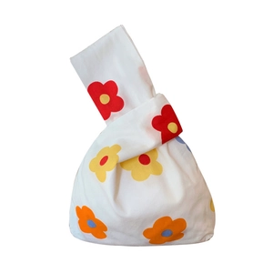 Japanese style wrist knot bag with vibrant colorful floral patterns on white canvas