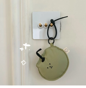 Detail of pea green fabric earphone case with cute face embroidery and black spiral lanyard
