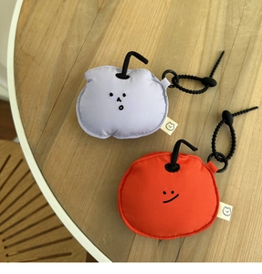 Close-up of cute knitted fruit-shaped earphone pouches in purple and red on a wood surface