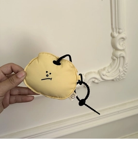 Detail of a soft yellow fabric earphone case with minimalist embroidery held by hand