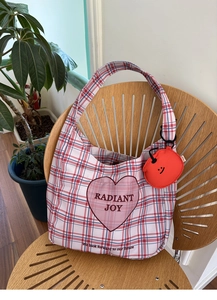 Detail of plaid earphone case with pink heart pattern and a red smiley face pendant
