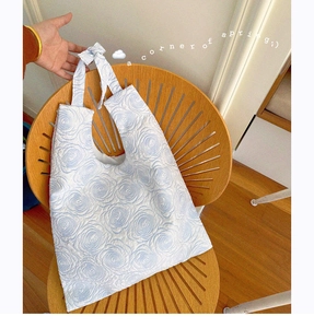 Detail of floral jacquard tote bag with blue rose pattern and bow handle decoration
