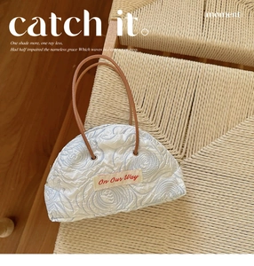 Detail of floral embossed texture and 'On Our Way' patch on white canvas tote bag