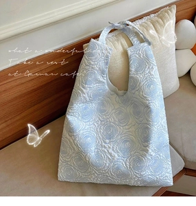 Detail of light blue tote bag featuring 3D embossed rose textures and quilted design