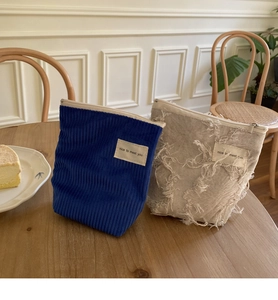 Detail van blauwe corduroy en crème katoenen zakjes met ritssluiting en stoffen label