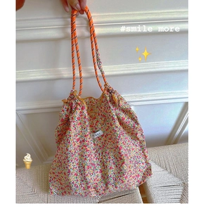 Close-up of floral canvas tote bag with orange woven rope handles and minimalist label