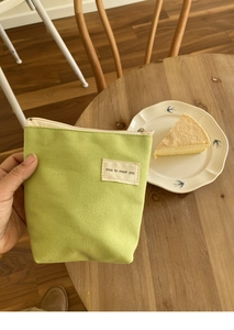 Close-up van een lichtgroene canvas tas met nice to meet you label op een houten tafel