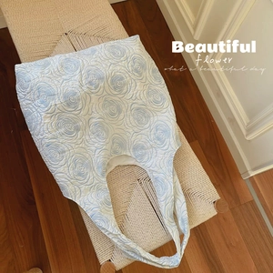 Quilted white tote bag featuring embossed blue rose patterns and integrated handles