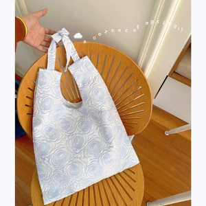 Blue tote bag with embossed floral pattern hanging on a vintage wooden chair