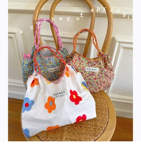Detail of floral canvas tote bags with woven handles on a vintage wooden chair