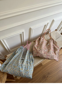 Detail of floral canvas tote bags with drawstring closure on a woven bench