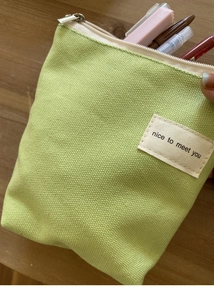 Detail van het lichtgroene canvas mini tasje met tekstlabel en metalen ritssluiting