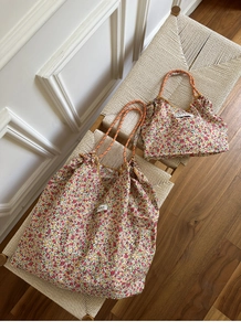 Detail of floral canvas tote bag set with orange rope handles on a woven chair