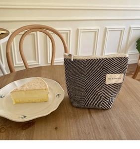 Detail van een zwart-wit gestreepte katoenen mini-make-uptas met rits op een houten tafel