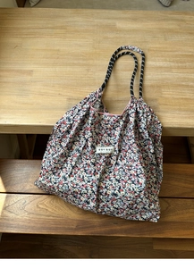 Close-up of floral canvas tote bag with woven stripe handles and a white fabric label