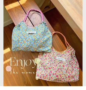 Detail of floral canvas tote bags with colorful braided rope handles and woven labels